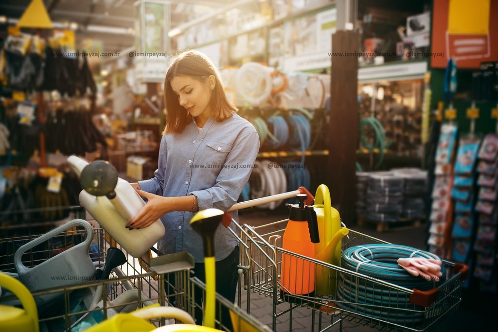 Bir kadın, bahçe malzemeleriyle dolu bir alışveriş arabasına bakarken görülüyor. Gün ışığı altında, Bir kadın, bahçe malzemeleriyle dolu bir alışveriş arabasına bakarken görülüyor. Gün ışığı altında, bahçe malzemeleri satan bir dükkanda alışveriş yap