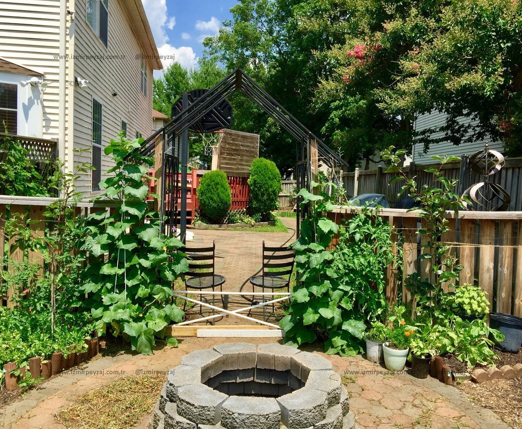 Bu resimde, bahçede bulunan bir ateş çukuru, bitki örtüsü ve oturma alanı görülmektedir. Bahçe düzenlemesi ve peyzaj detayları dikkat çekmektedir.