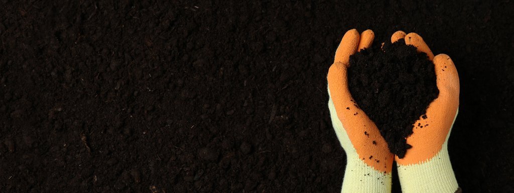 Bahçe toprağı ile dolu eldivenli ellerin yakın çekim görüntüsü. Verimli toprak ve bahçecilik temalı görsel.