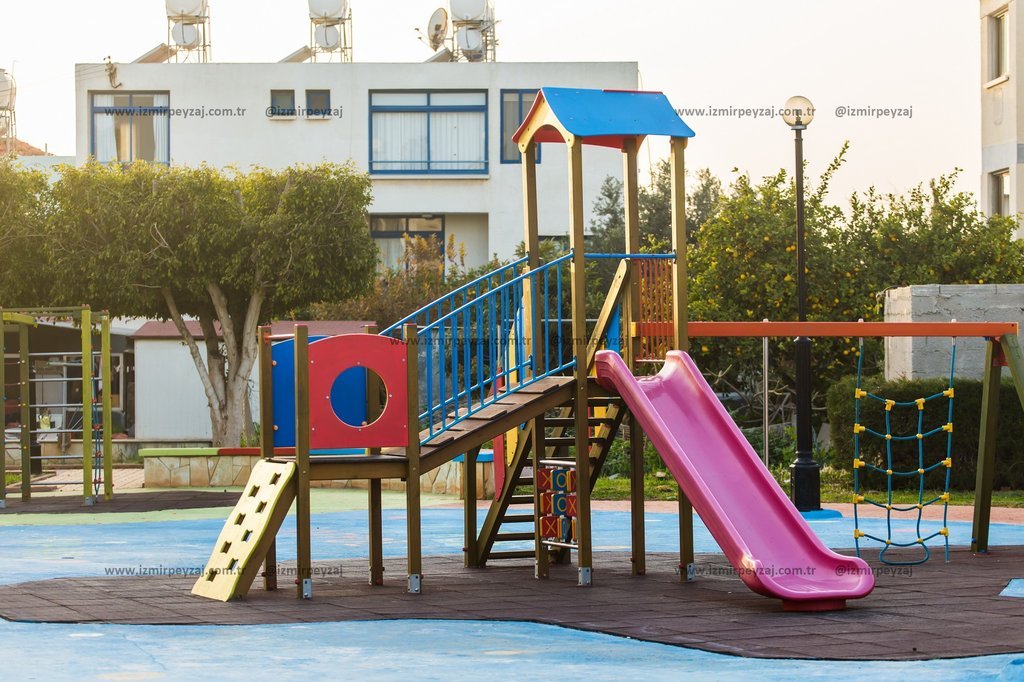 Çocuk parkında bulunan oyun parkı ve kaydırağın görüntüsü. Renkli tasarımı ile çocukların eğlenceli vakit geçirebileceği bir alan.