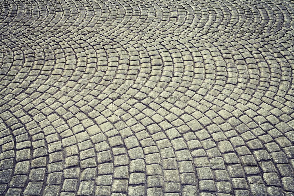 Bu fotoğrafta, dairesel bir desen oluşturan taş döşemeli bir zemin görülmektedir. Taşların düzeni, görsel olarak ilgi çekici ve dinamik bir etki yarat