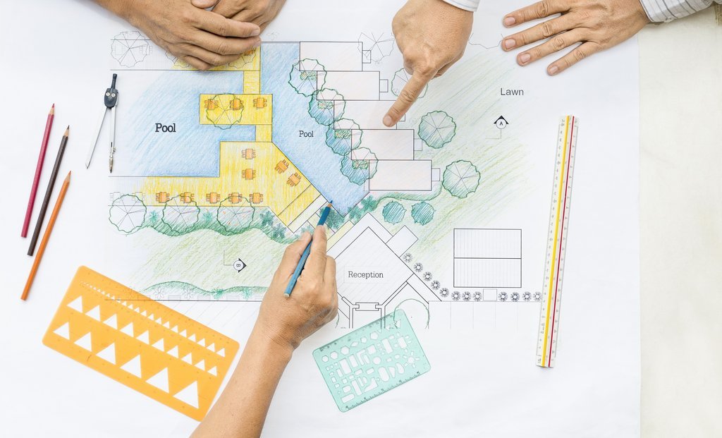 Mimarlar, havuz ve bahçe düzenlemesi içeren bir peyzaj planı üzerinde çalışıyorlar. Teknik çizim det Mimarlar, havuz ve bahçe düzenlemesi içeren bir peyzaj planı üzerinde çalışıyorlar. Teknik çizim detayları ve renkli kalemlerle yapılan tasarım, proje