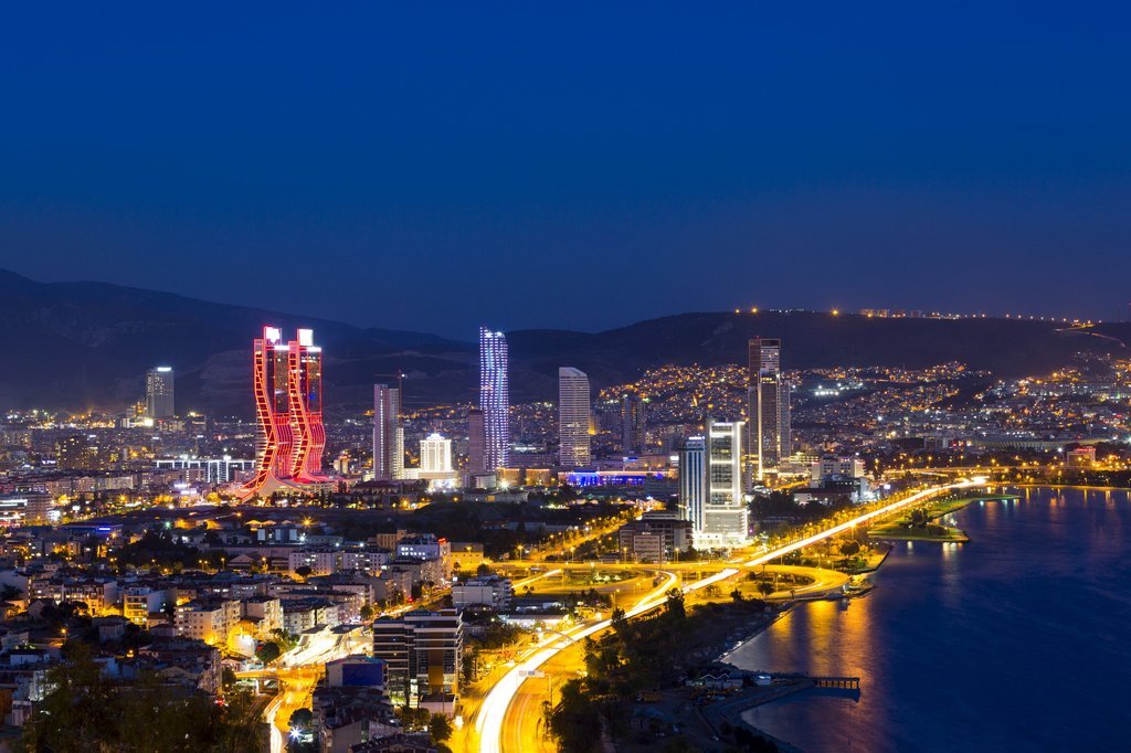 İzmir şehrinin gece manzarası, ışıklandırılmış gökdelenler ve hareketli şehir yaşamını yansıtan uzun İzmir şehrinin gece manzarası, ışıklandırılmış gökdelenler ve hareketli şehir yaşamını yansıtan uzun pozlama trafik ışıkları ile büyüleyici bir görsel