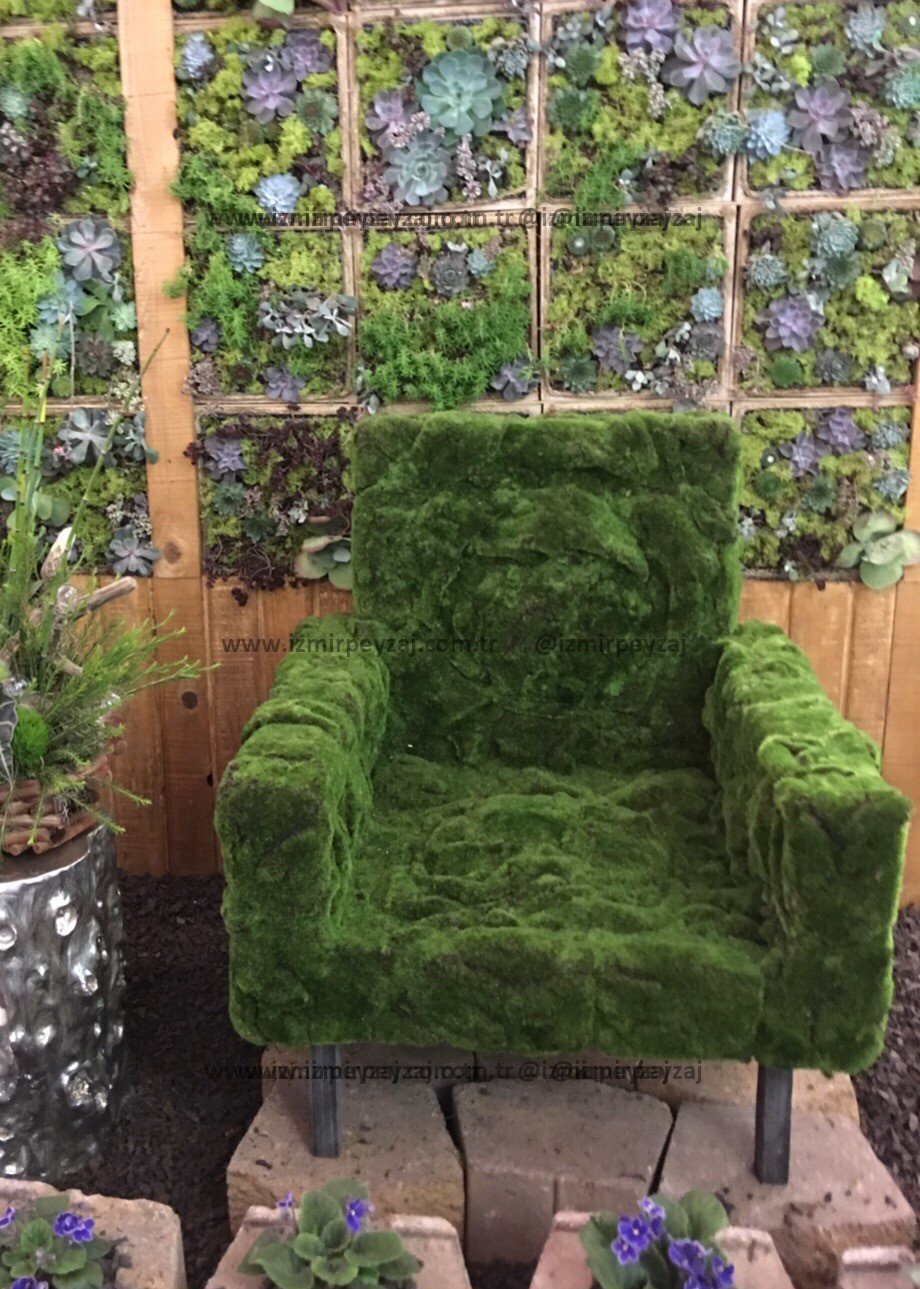 Yeşil bitki örtüsüyle kaplı bir koltuk, doğal ve sıra dışı bir tasarım örneği sunuyor. Duvarlardaki Yeşil bitki örtüsüyle kaplı bir koltuk, doğal ve sıra dışı bir tasarım örneği sunuyor. Duvarlardaki bitki panelleriyle uyum içinde, doğayı iç mekanlar