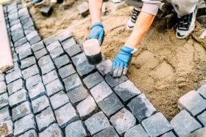 industrial construction worker, handyman using cobblestone granite stones for creating walking path